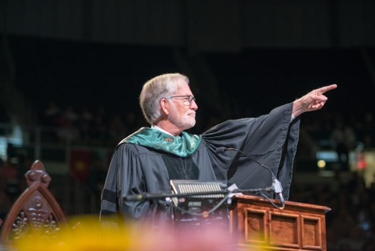 David Crane points at the audience while speaking at an Ohio University Commencement Ceremony