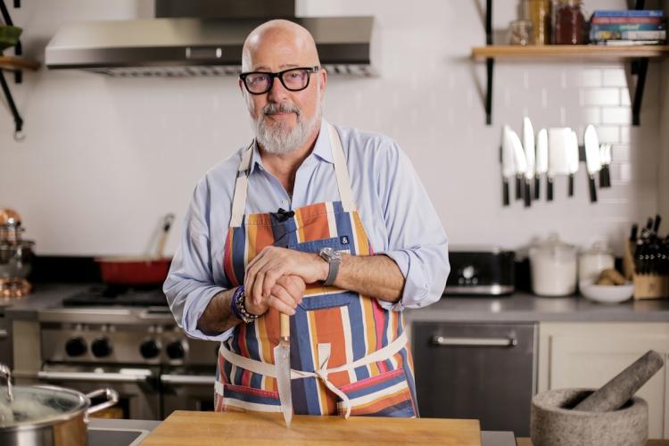 Andrew Zimmern is shown at a counter in a kitchen