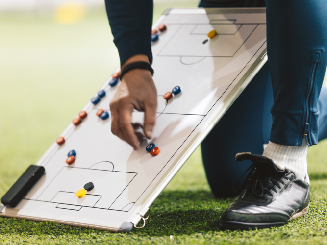 coach kneeling showing plays on a whiteboard
