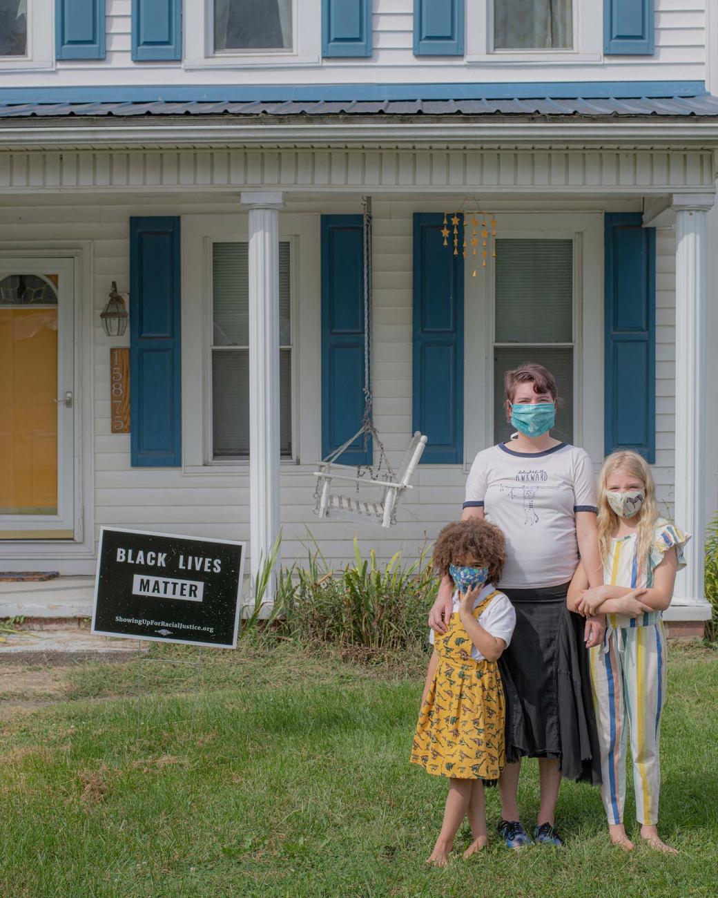 The Handley family posing in their front yard next to their yard sign