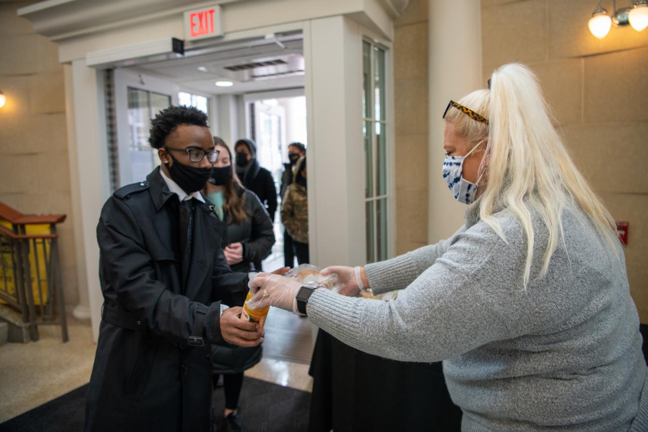 A Culinary Services employee hands out take out brunch for Silent March participants at Baker Center.