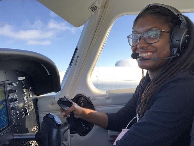 A woman smiles while flying a small plane