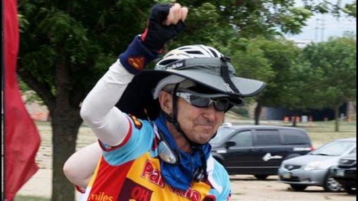 Jim Bond holds his arm up on a bike