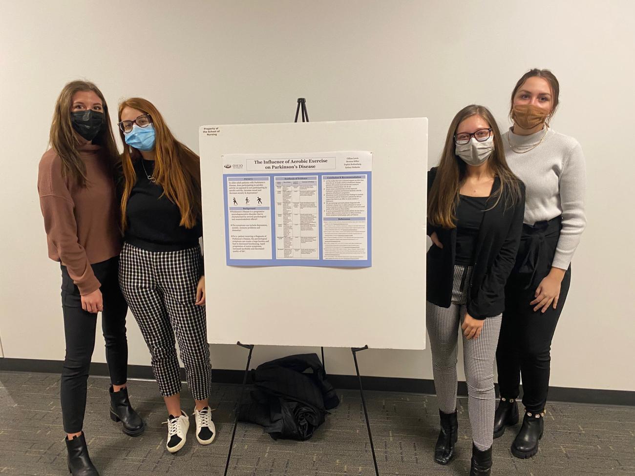 Students stand around a poster board.