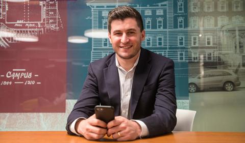 Aaron Schwarz holding a cell phone while sitting at a desk