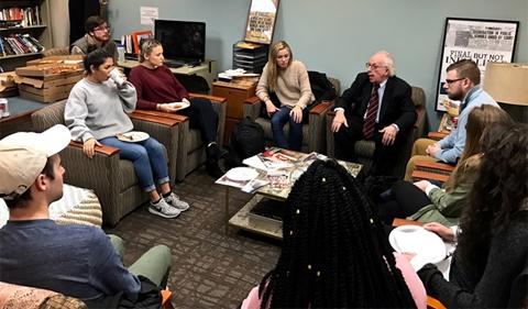 Alan Rom sitting with students