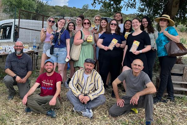 Food in Sicily students and faculty holding Dolci Evasioni products with members of the social cooperative L’Arcolaio in the foreground.