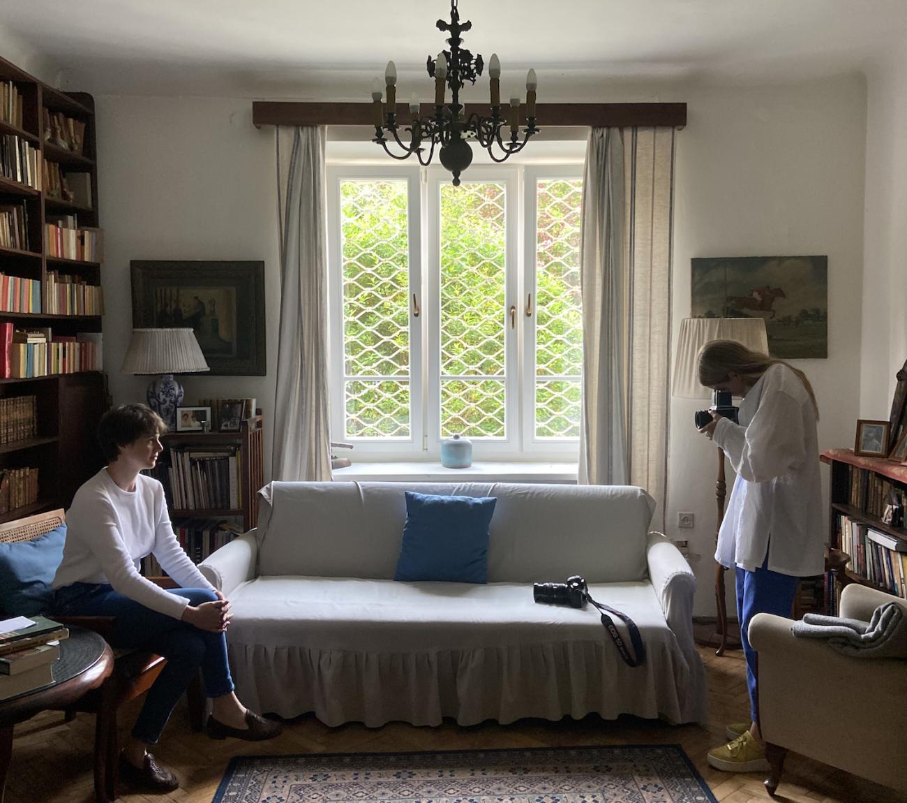 Madeleine Hordinski on the right photographs a person sitting in front of her in a small room