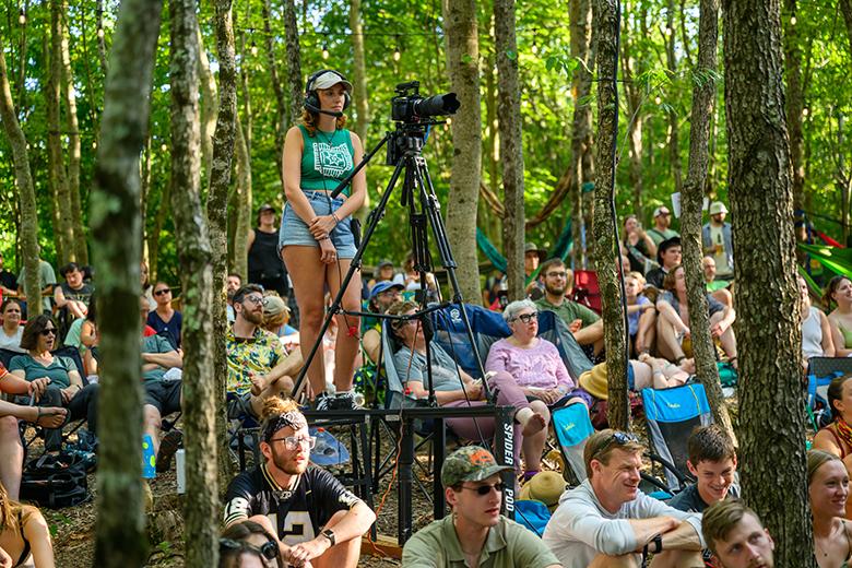 An OHIO student positioned in the middle of the audience operates one of several cameras filming the Creekside Stage.