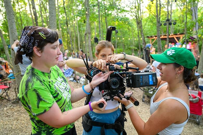 Three Ohio University students troubleshoot a camera with a weighted gimbal at the Creekside Stage.