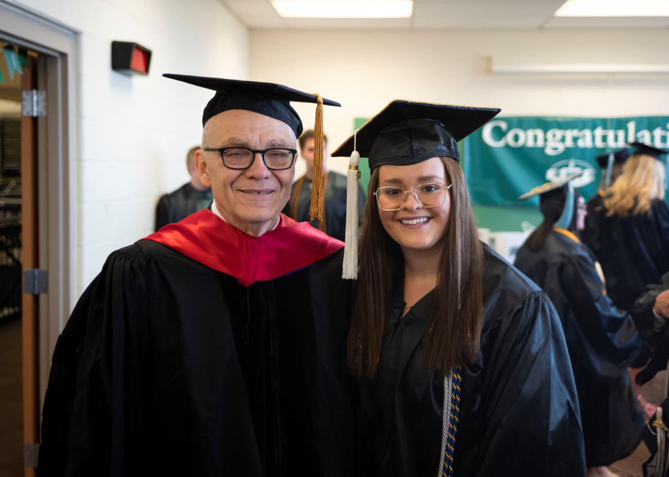 Professor and Graduate dressed in regalia