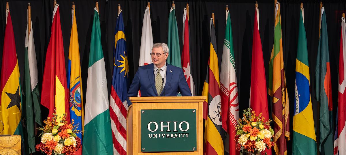 Donald Leo speaks before international flags at the Global Engagement Awards ceremony