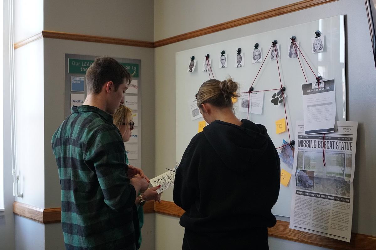 OHIO students look at a wall filled with clues related to the mystery