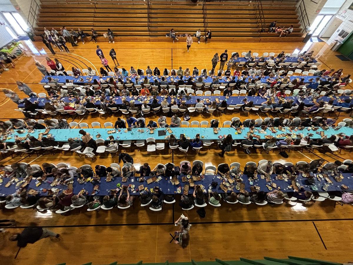 An overhead image of students filling up the tables and chairs in the gymnasium at the STEM Discovery Day event
