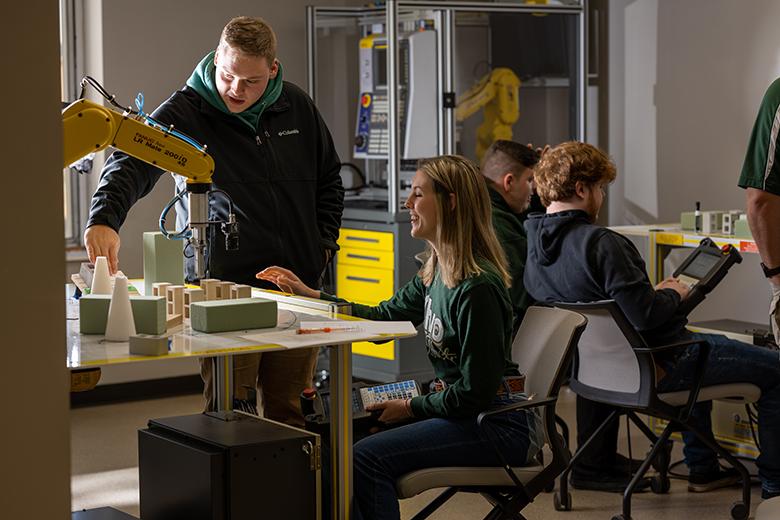 Two OHIO Lancaster students work with robotics and automation equipment.