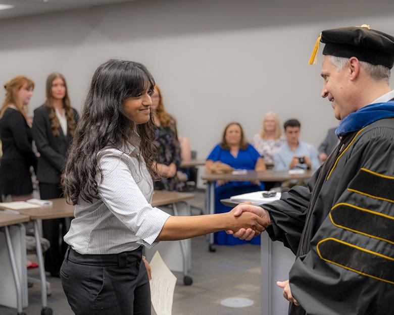 CHSP Dean and PBK President John McCarthy shakes the hand of a student.