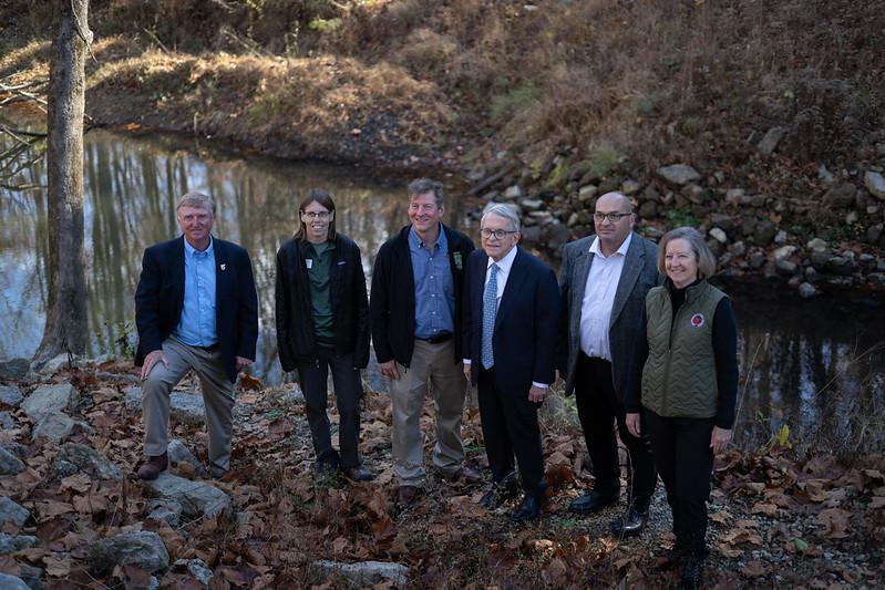 State and local leaders stand beside Raccoon Creek