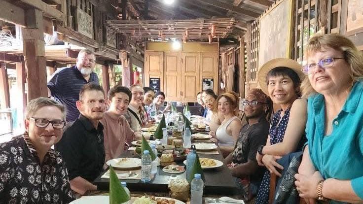 OHIO students and faculty sit together at a table at a restaurant in Thailand