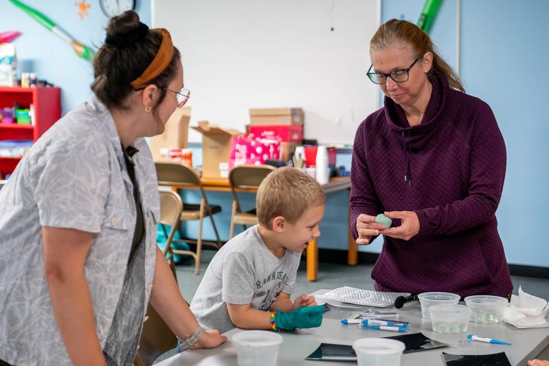 Two teachers work on a science project at a table with an elementary school student