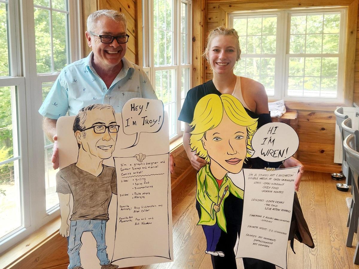 Wren Denny and Troy Sayers hold up the caricatures they created