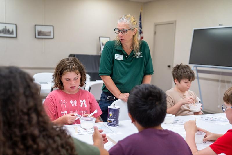 An OHIO representative watches local children work on a science  project at a Library STEM Day event