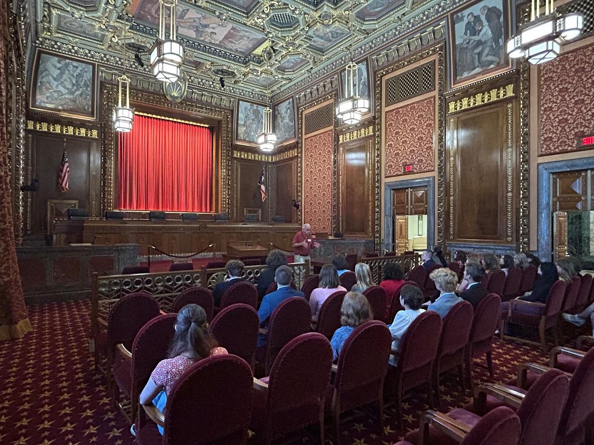 Participants in the Summer Law and Trial Institute are shown listening to a speaker while sitting in the Supreme Court of Ohio courtroom