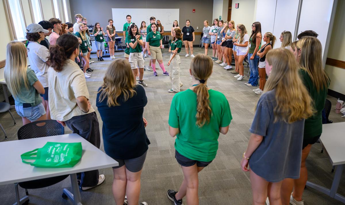 Orientation leaders lead a presentation and stand inside a group of students and family members while inside a large room during Bobcat Student Orientation