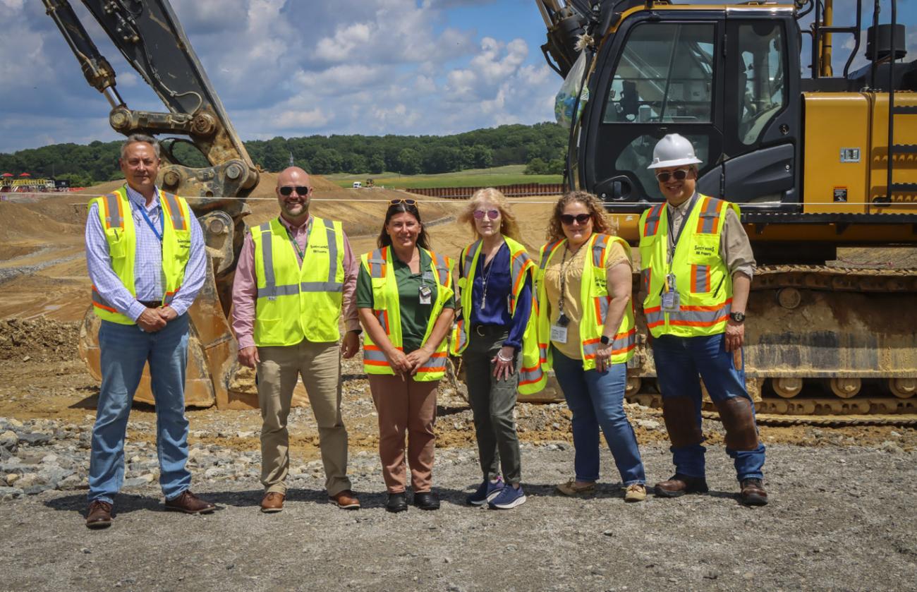 OHIO representatives stand in front of earth moving equipment at a project development site