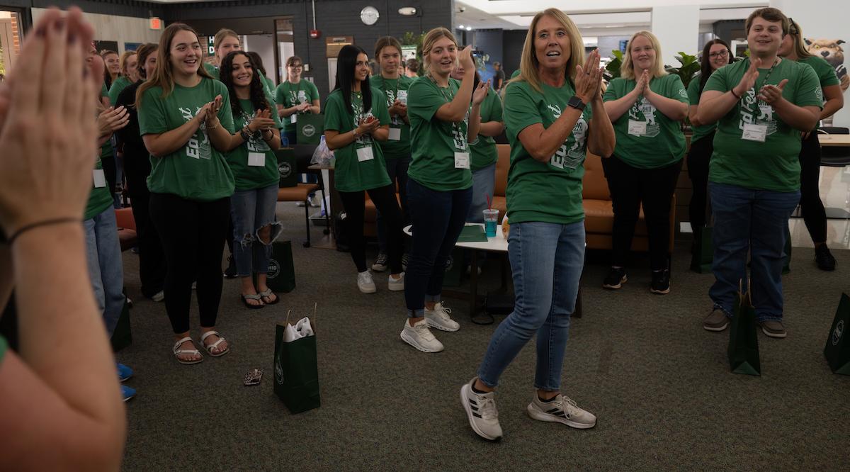 a faculty member leads a group of students in singing Stand up and Cheer