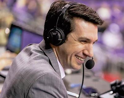 a close-up of sports broadcaster Tony Castricone wearing a gray suit and a microphone headset