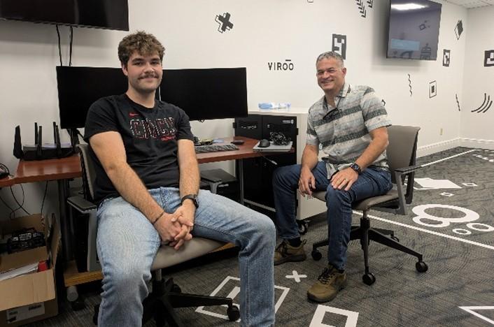 Two individuals sit in an OHIO laboratory room near computer screens