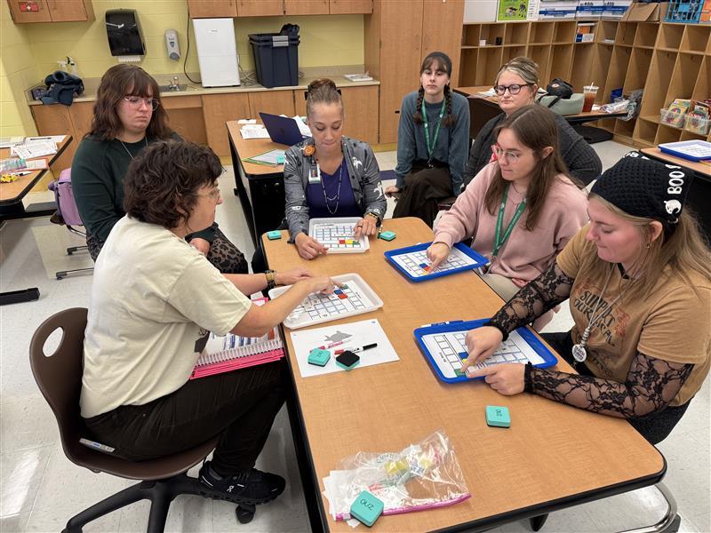 OHIO students and Zane Grey Elementary School teachers work on a project while sitting in a classroom in the elementary school