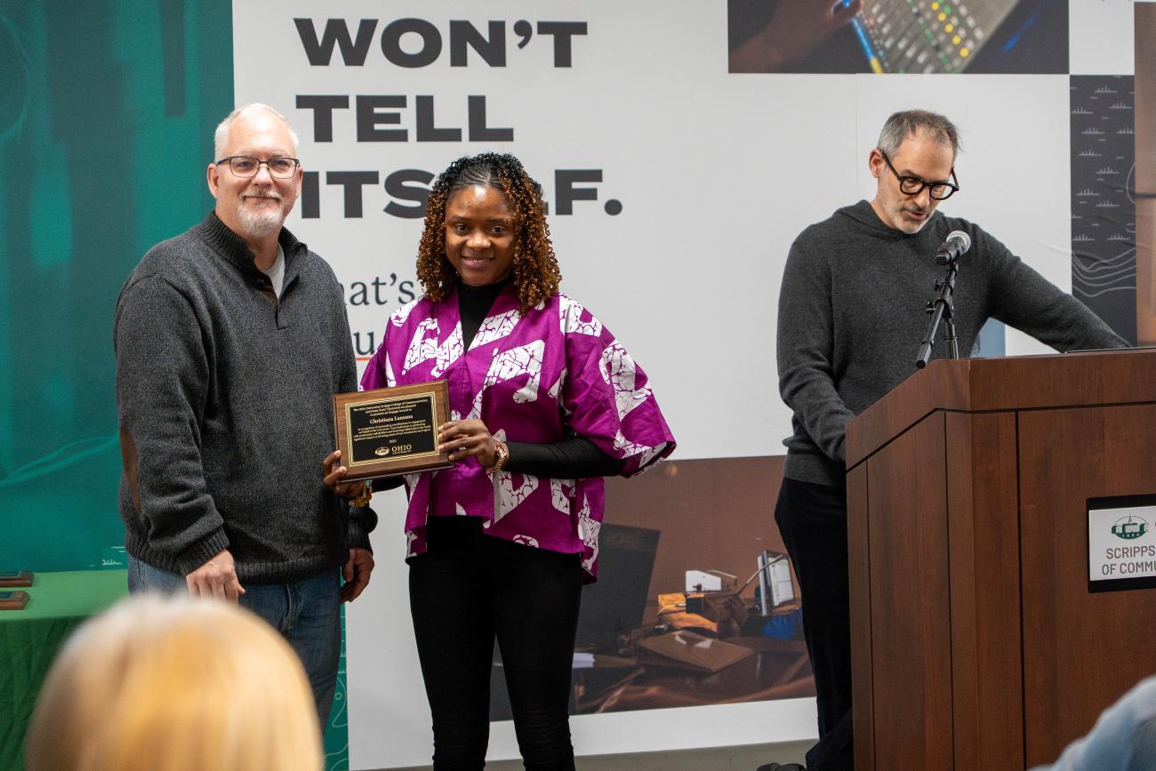 Dean Titsworth hands a plaque to Christiana Lansana