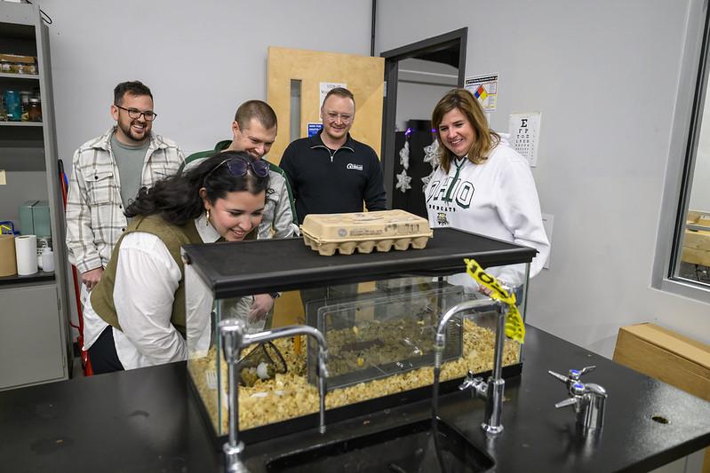 Students and teachers look over a STEM project in a classroom.