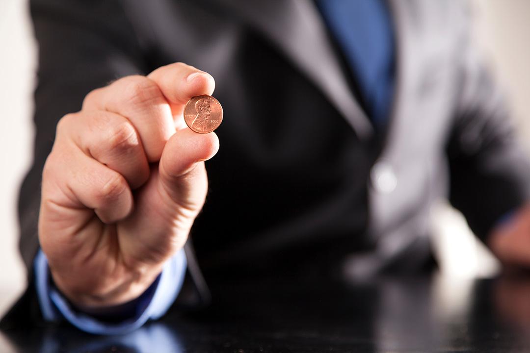 A businessman holds a penny.