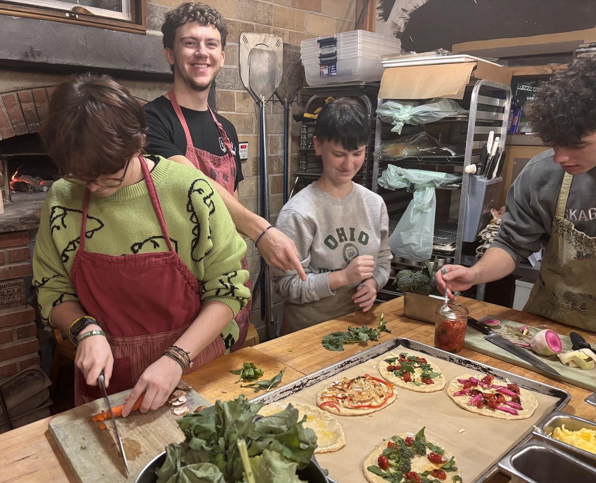 Learning Community students and instructor work together making pizzas in a kitchen