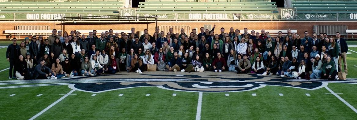 Representatives of the OHIO - LAIOB partnership stand together for a group photo on the football field at Peden Stadium