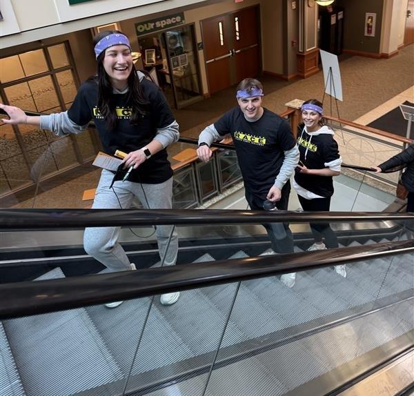 Three participants in the Leader Games Challenge ride up the escalator in the Baker University Center