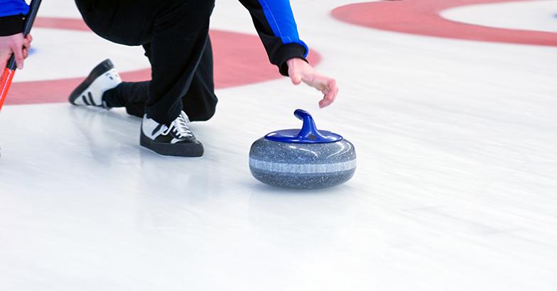 An Olympic curler guides a stone toward the house.
