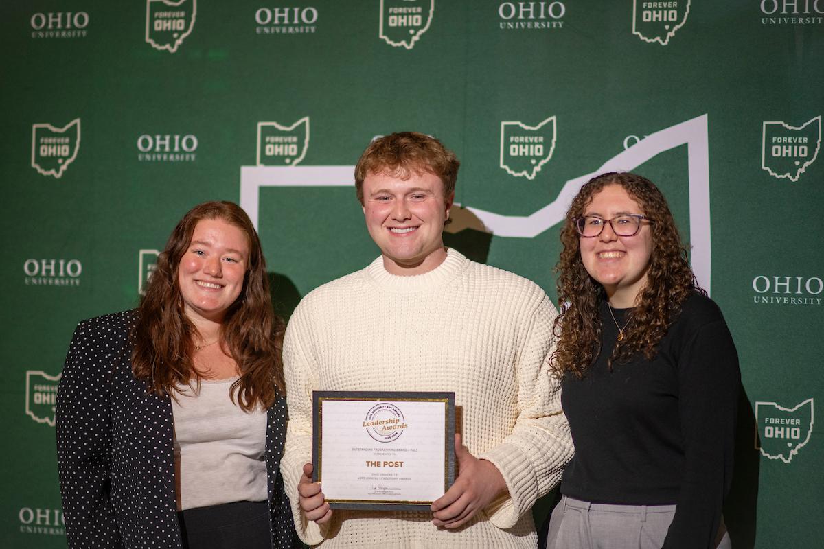 Three representatives of The Post stand together and hold the Leadership Award