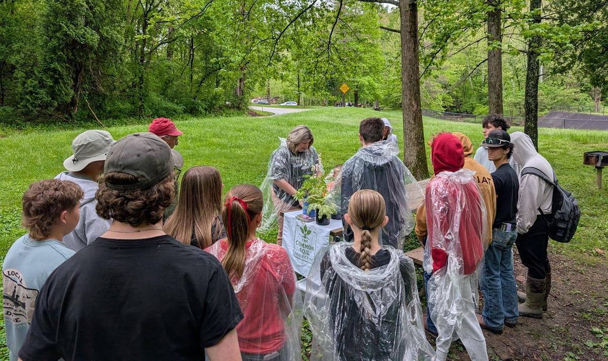 A group of students watch an expert do a presentation at table outside at the Wayne National Forest