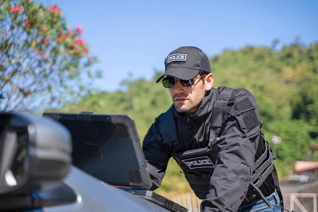 A stock image of a law enforcement officer working on a laptop