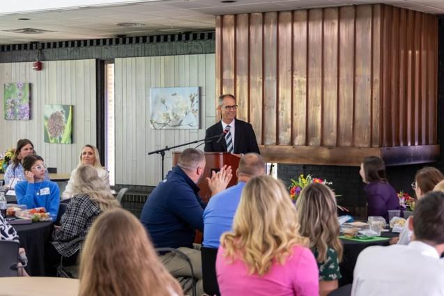 Michael Lafreniere stands at a podium in front  of an audience and provides remarks