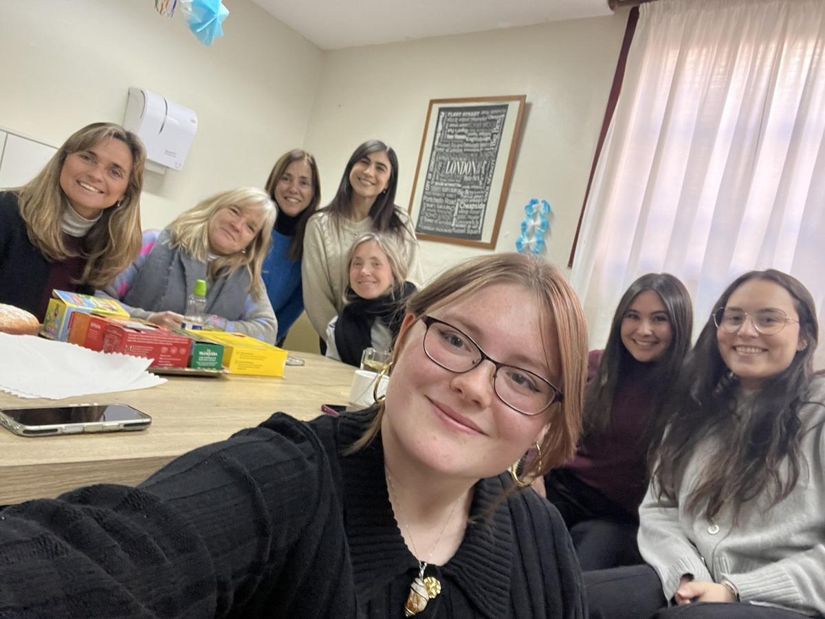 McKenna Thomas poses with a group of other people while they sit around a table during her internship in Greece.