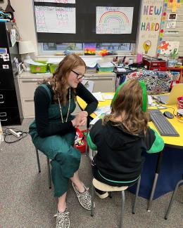 Teacher helping a child with reading in a classroom