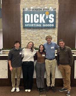 a group of four students and one faculty advisor pose at Dick's Sporting Goods headquarters