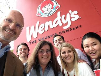 a professor and five students stand in front of the Wendy's corporate sign