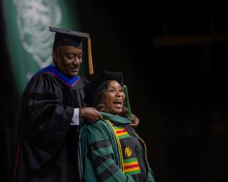 HCOM graduate is hooded by mentor