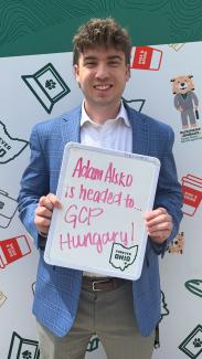 OHIO COB student Adam Alsko holding a sign saying he is heading to Hungary for the university's Global Consulting Group program this summer.