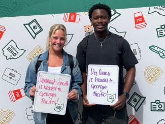OHIO COB students Savannah Smith and Des Owusu holding signs that say they are goin gto Georgia Pacific for their summer internships.